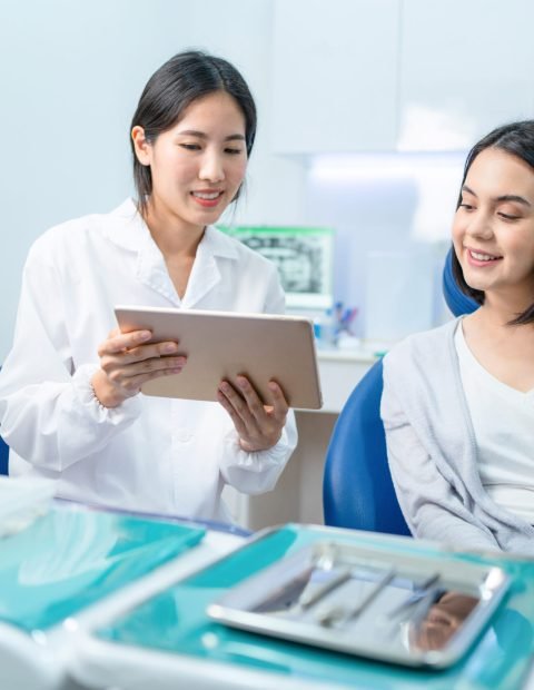 asian-dentist-holding-digital-tablet-and-giving-ad-2023-11-27-05-28-36-utc